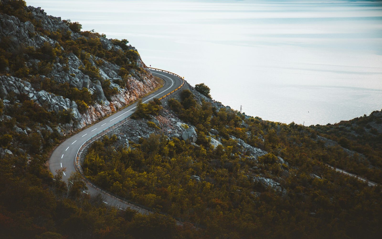 A winding coastal mountain road curving high above a calm sea
